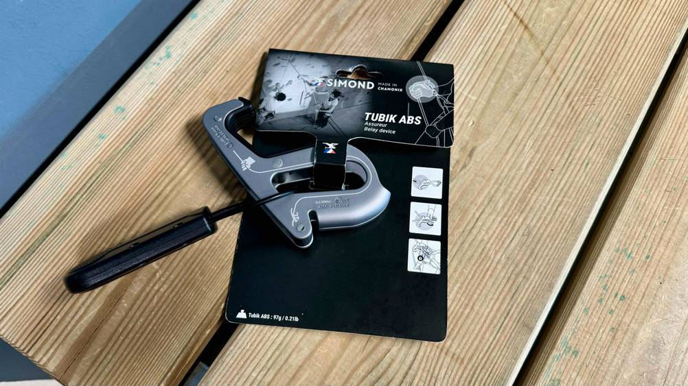 Sicherungsgerät für das Klettern getestet: Ein Gerät originalverpackt auf einer Holzfläche.