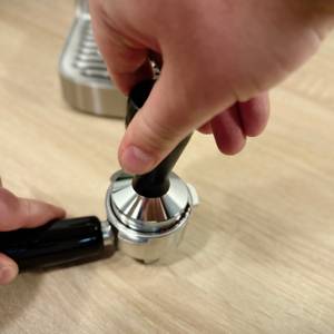Mit einem Tamper wird das Kaffeemehl für die Siebträgermaschine von Caso verdichtet.