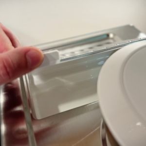 Das Zubehörfach unterhalb der Tassenablage wird geöffnet.