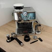 Der gesamte Lieferumfang der Delonghi-Siebträgermaschine ist auf einem Tisch ausgebreitet.