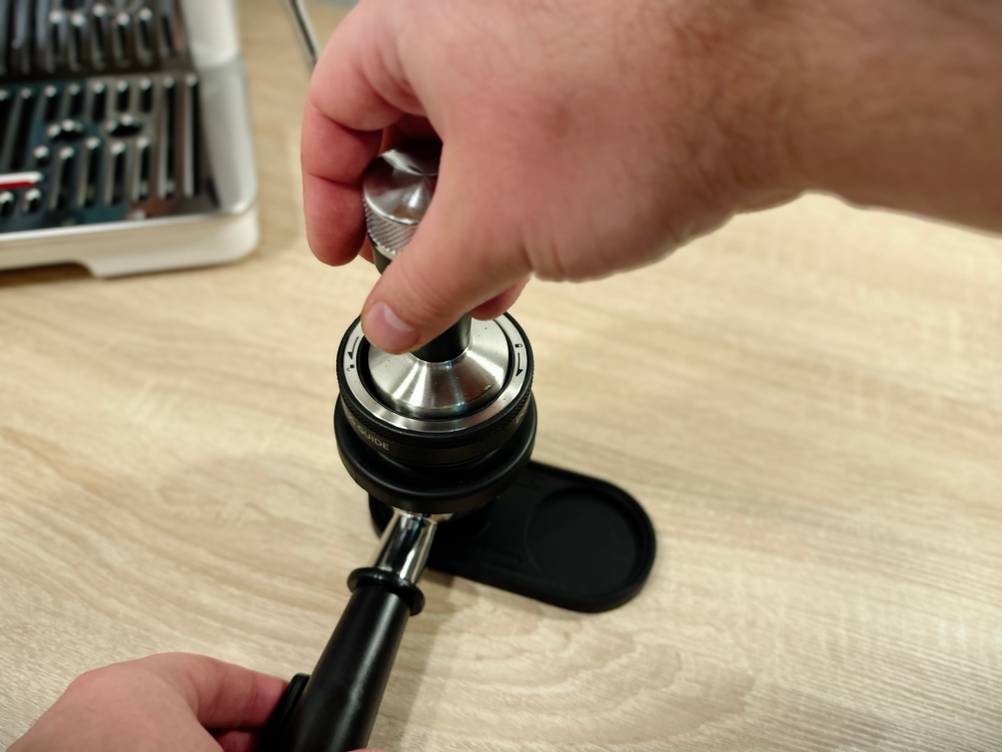 Mit einem Tamper wird Kaffeepulver verdichtet.