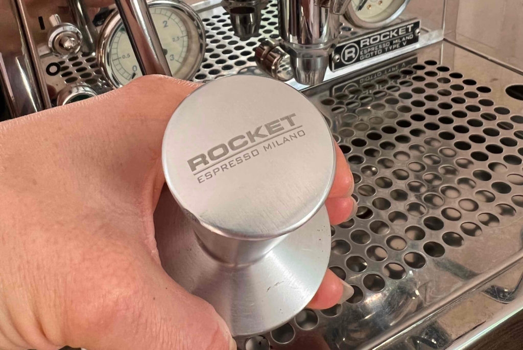 Siebträgermaschinen-Test: Hand hält Zubehör einer Siebträgermaschine. 