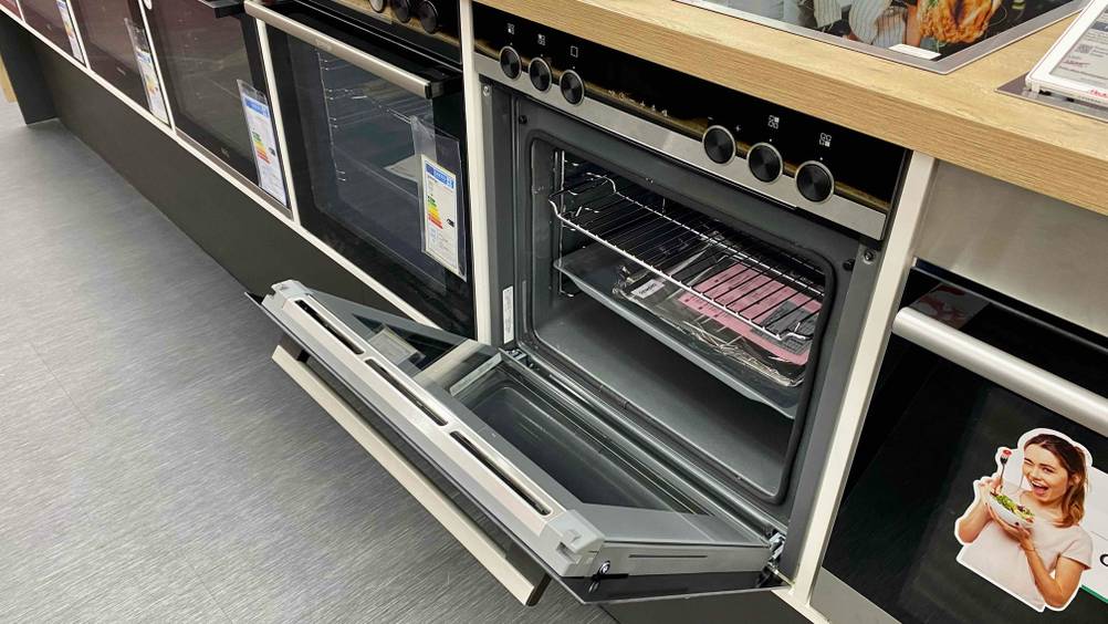 Ein Siemens-Backofen im Test mit geöffneter Klappe von leicht seitlich neben anderen eingebauten Geräten.