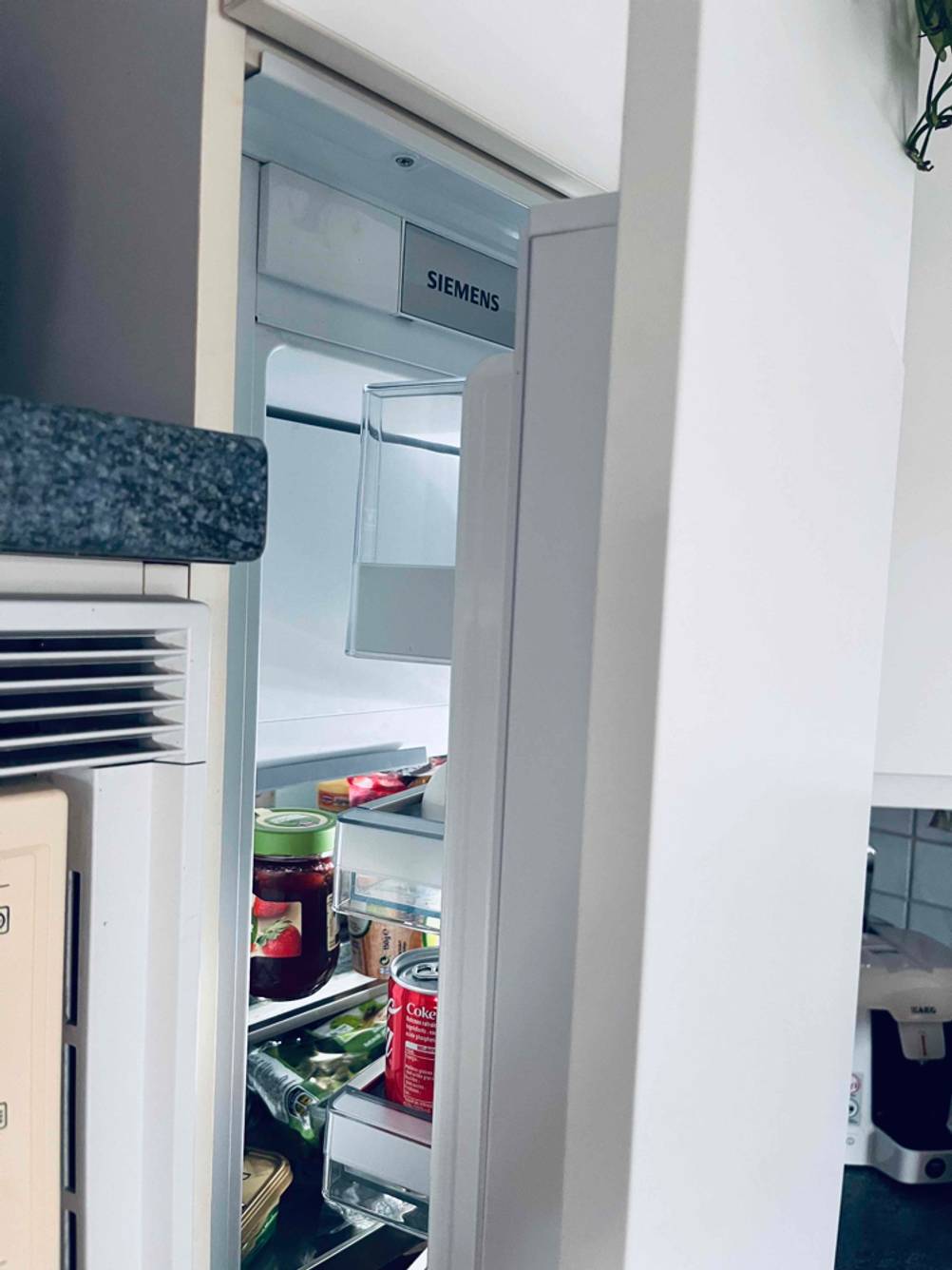 Siemens Einbaukühlschrank im Test steht mit geöffneter Tür in einer häuslichen Küche.