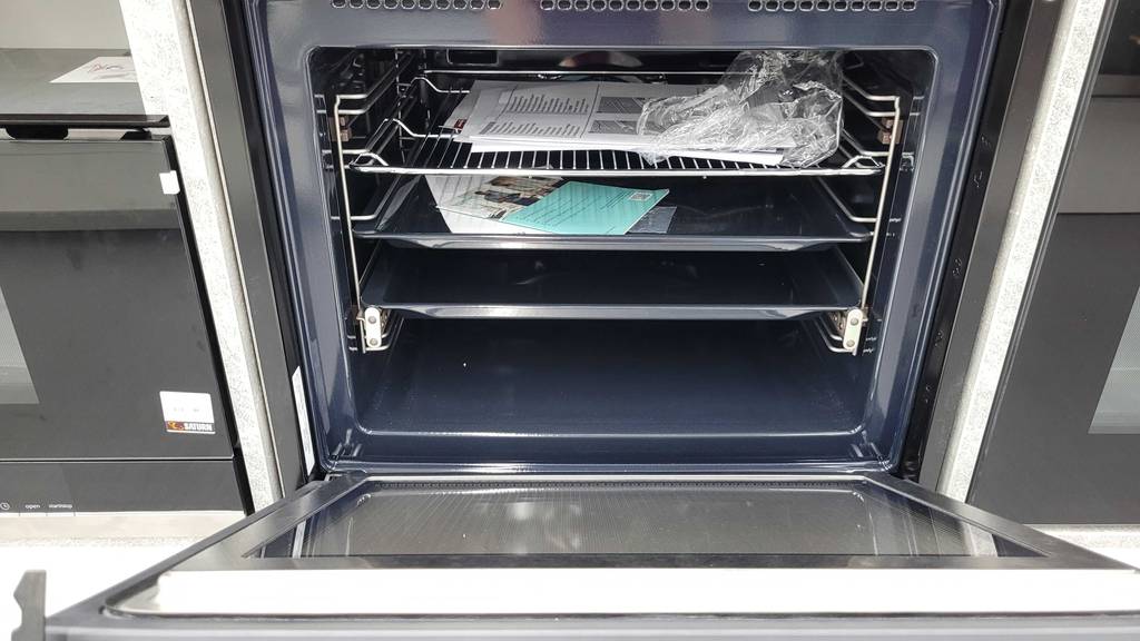 Ansicht von oben vorn auf einen geöffneten und getesteten Kombibackofen mit drei Teleskopauszügen und Backblechen.