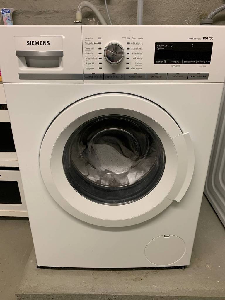 Siemens-Waschmaschine-Test: ein iQ700 Modell steht mit Wäsche in der Trommel in einem Waschraum.