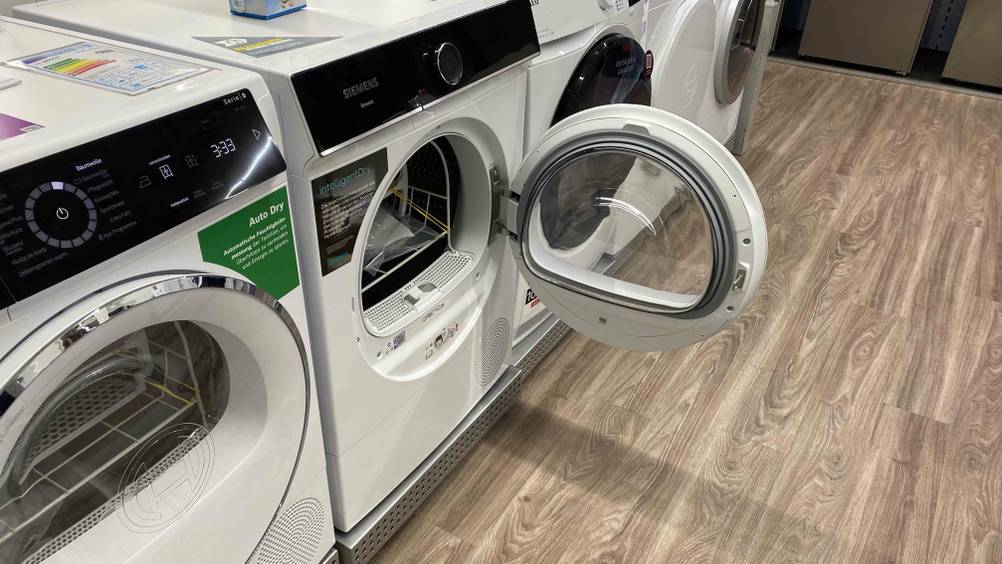 Siemens-Trockner getestet: Ein Gerät mit geöffneter Klappe zwischen anderen Geräten in einer Verkaufsfläche.