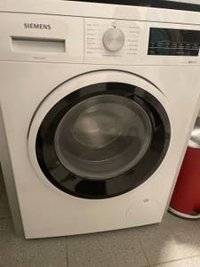 Waschmaschine im Test: Siemens Frontlader steht mit geschlossener Tür auf grauen Fliesen.