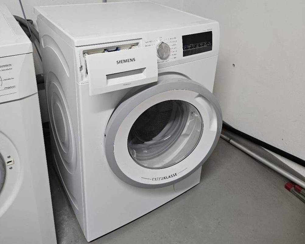 Waschmaschine im Test: Siemens-Modell Extra Klasse steht mit leicht geöffneter Tür in einem Waschraum.
