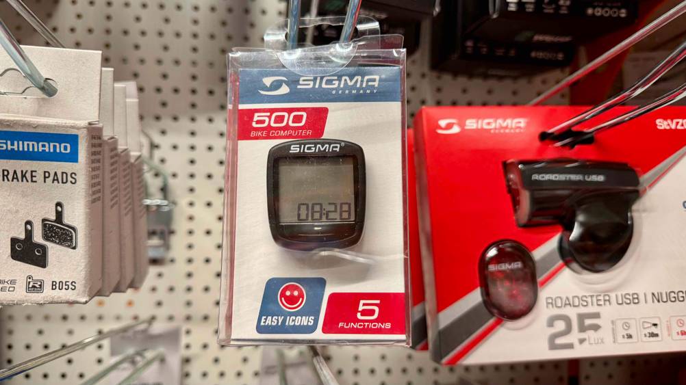 Der Sigma-Fahrradcomputer im Test hängt in einem Verkaufsregal neben anderen Produkten.