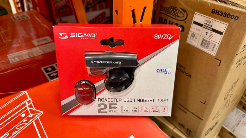 Ein getestetes Sigma-Fahrradlicht lehnt in Verpackung an ein Metallregal.