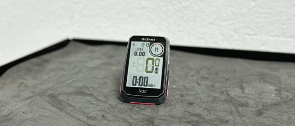 Das Sigma Sport ROX 4.0 steht auf einer Werkbank. Das Display ist aktiviert und zeigt typische Fahrrad-Daten an.