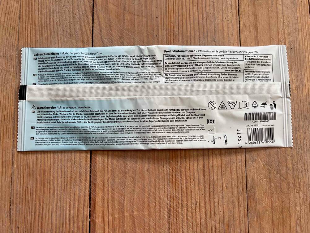 Im Test: Rückseite einer verpackten FFP2-Maske auf einer Holzfläche.