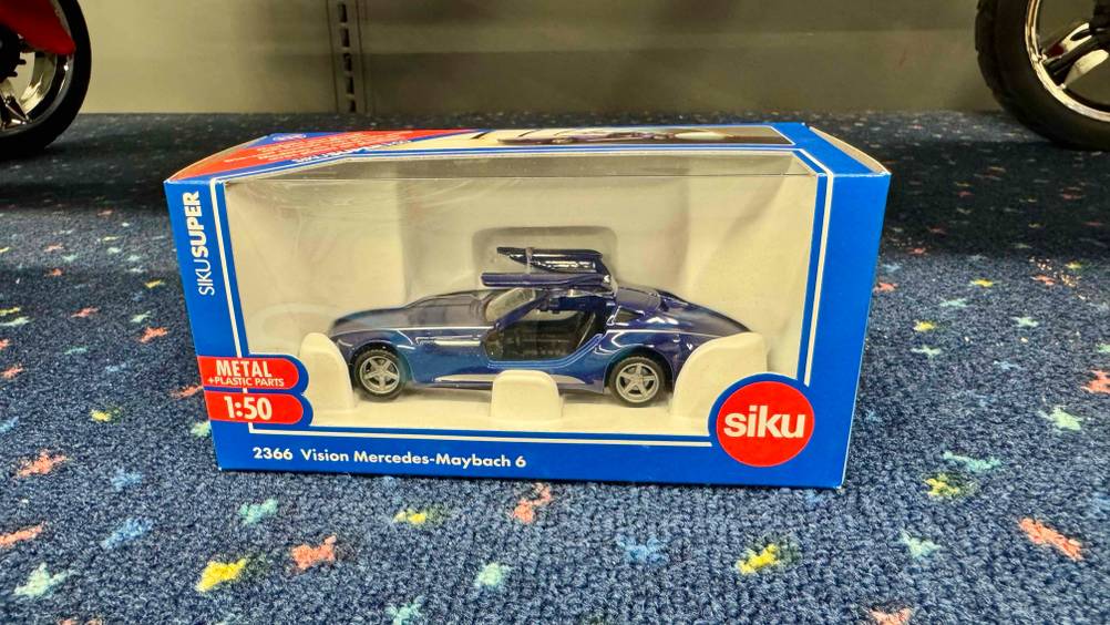 Auf einem Teppichboden steht das Siku-Auto im Test in der transparenten Originalverpackung.