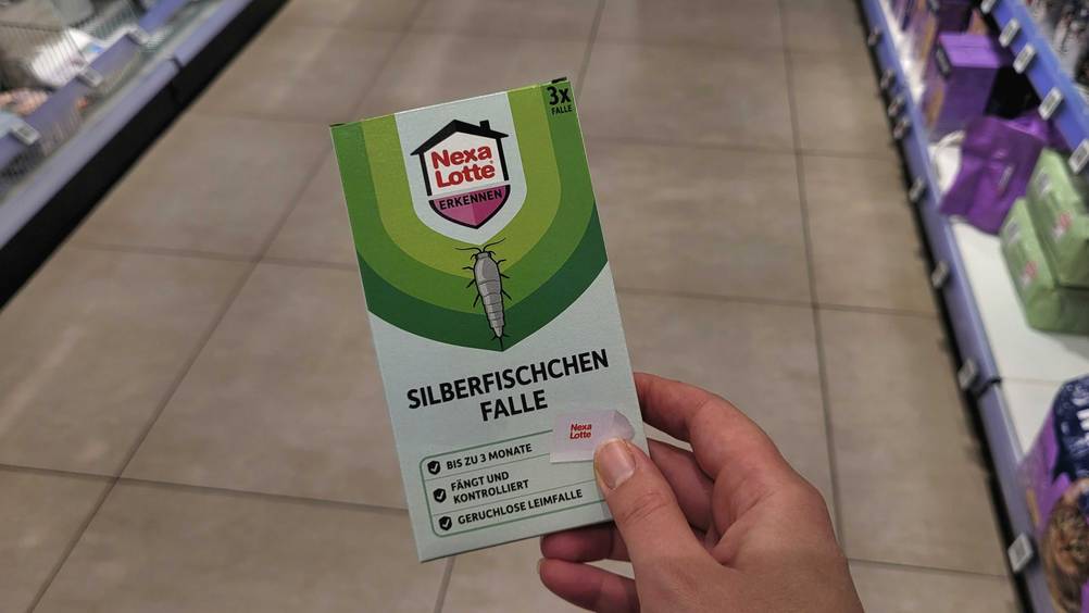 Eine Hand hält eine Packung der Silberfischfalle im Test hoch.