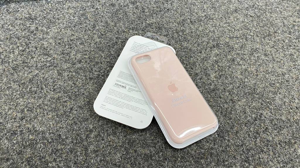 Im Test: Eine Packung IPhone SE Hülle liegt schräg auf einer zweiten, die mit der Rückseite nach oben auf dunkler Fläche liegt.