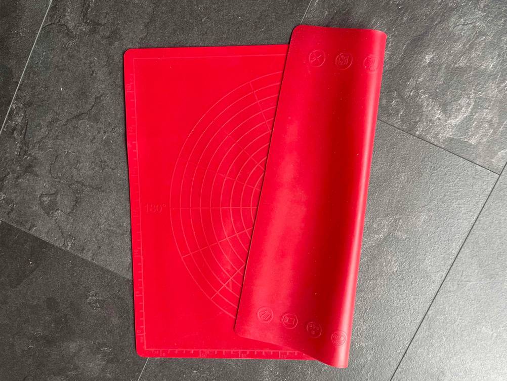 Eine zusammengefaltete Silikon-Backmatte im Test auf einer dunklen Fläche, beide Seiten mit unterschiedlichen Prägungen.