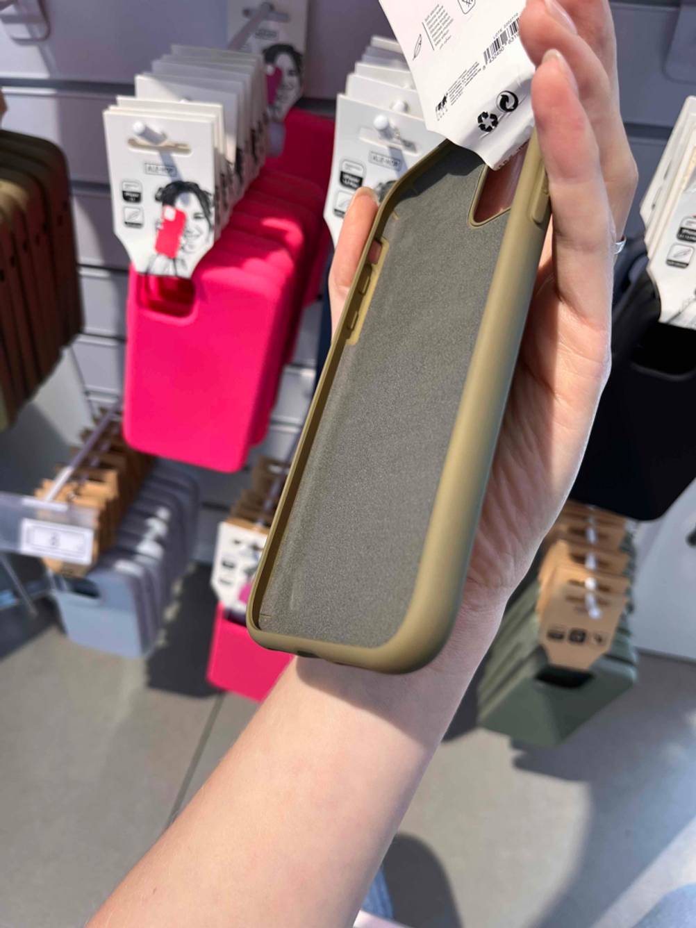 iPhone-11-Pro-Max-Hüllen im Test: Eine Hand hält die goldfarbene Hülle, mit Fokus auf die Innenseite, vor einem Verkaufsregal.