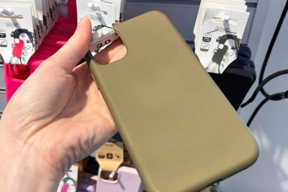 Hand zeigt die Rückseite einer olivgrünen iPhone 11 Pro Max Hülle im Test. Im Hintergrund weitere Smartphone-Hüllen.