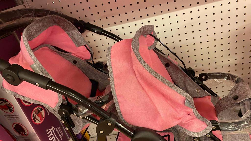 Nahaufnahme der Sitze inklusive Sonnenschutz von einem getesteten Zwillingspuppenwagen in Rosa-Grau.
