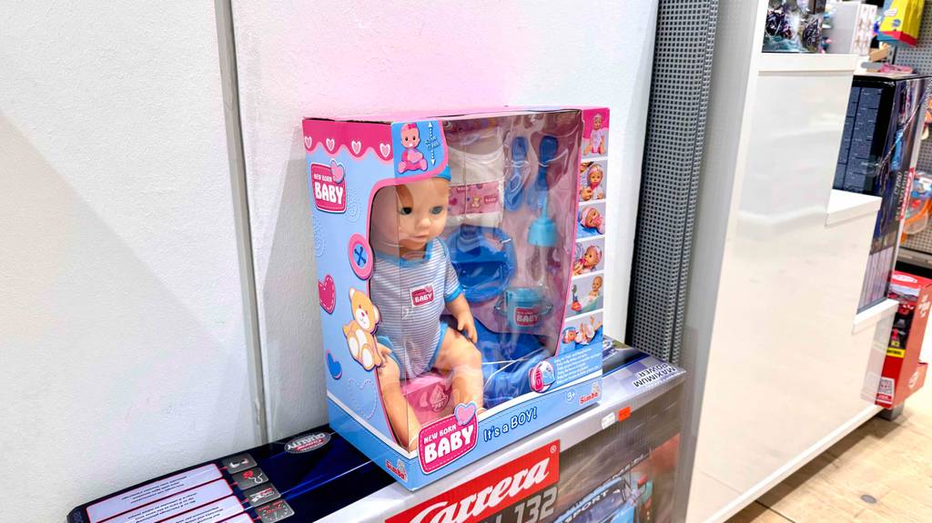 Eine verpackte Babyborn steht zum testen auf einem Rennbahnkarton.
