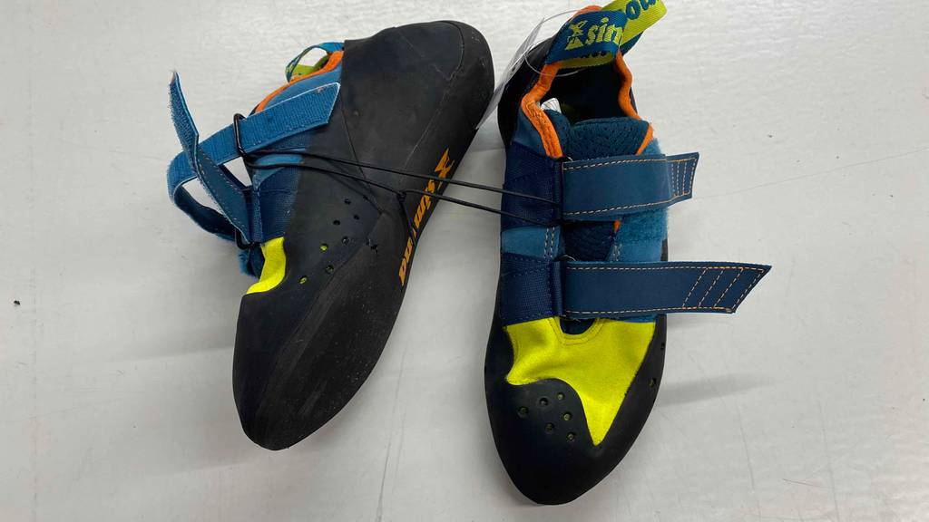 Im Test: Ein Paar Kletterschuhe von Simond auf weißer Fläche, einer davon liegend mit Sohlenansicht.