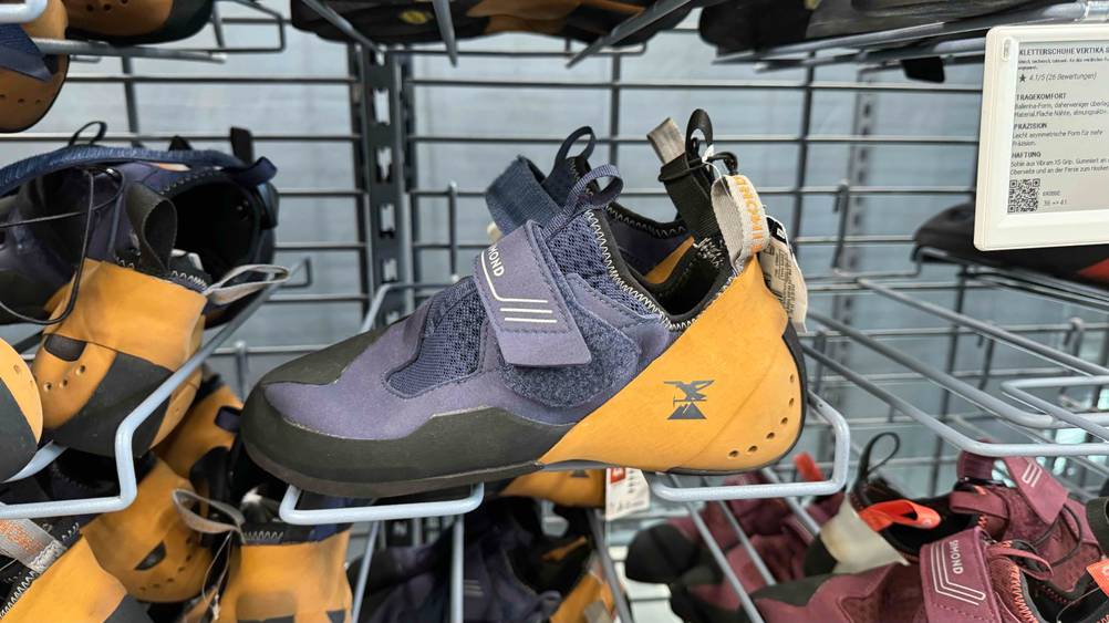 Kletterschuhe im Test: Seitenansicht mit Blick auf den Klettverschluss auf einen Schuh, der in einem Regal mit vielen anderen Schuhen steht.