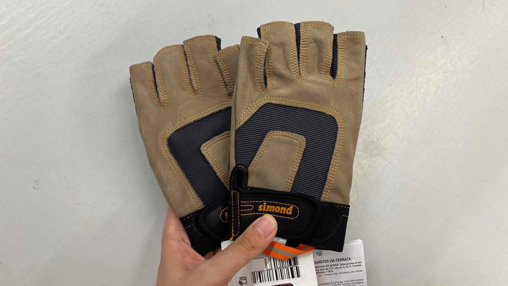 Im Test: Hand hält ein Paar Simond Klettersteighandschuhe vor weißer Wand.