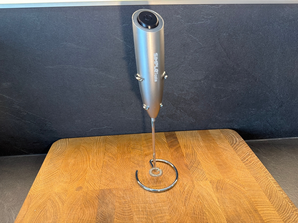 Der Simpletaste-Milchaufschäumer steht auf einer Holzplatte