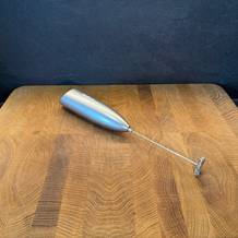 Der Simpletaste-Milchaufschäumer liegt auf einer Holzplatte