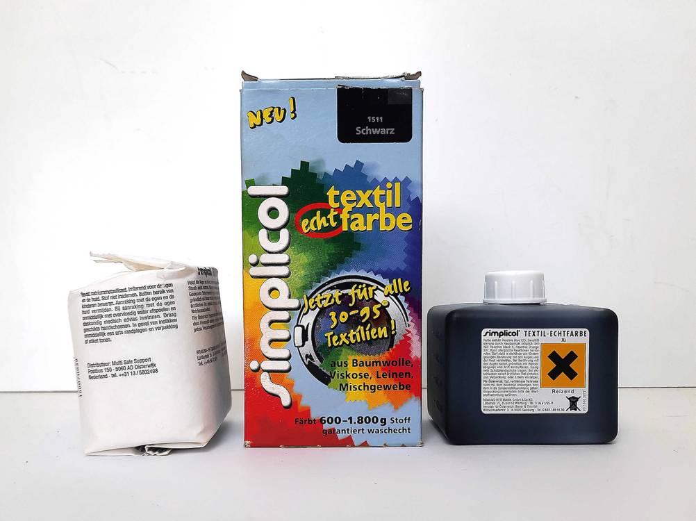 Ein Set mit Textilfarbe schwarz zum testen steht vor einer weißen Wand.