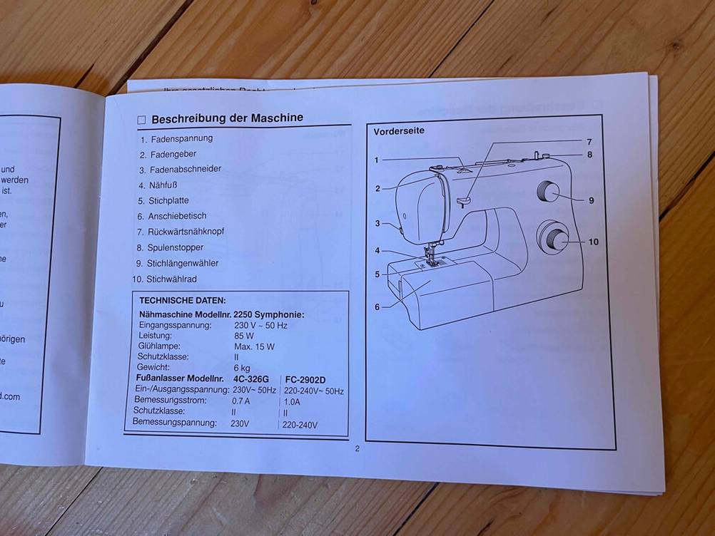 Im Test: Bedienungsanleitung einer Singer-Nähmaschine mit Grafik auf einem Holzboden.