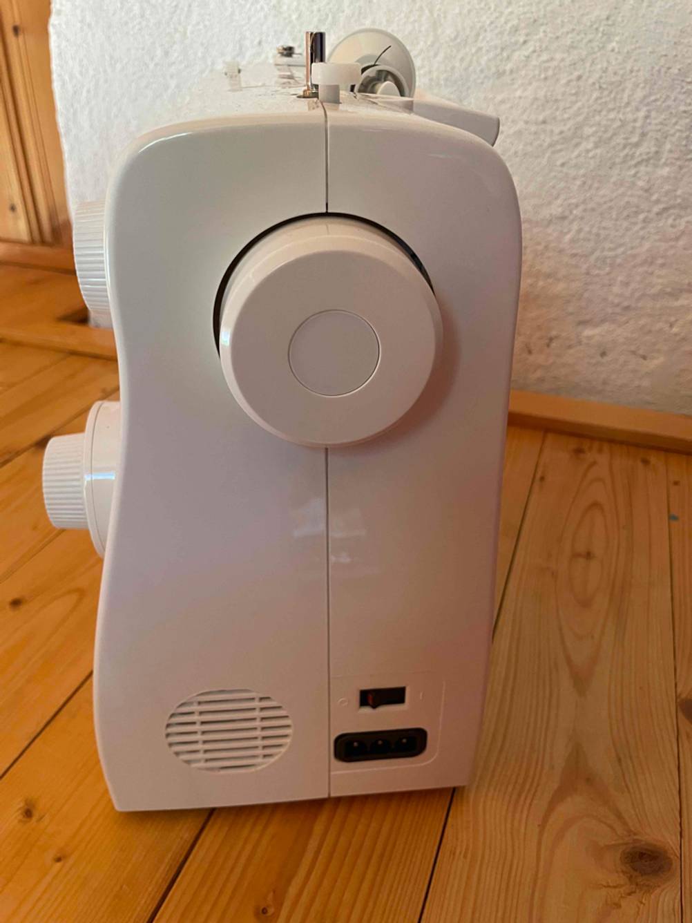 Nahaufnahme des Handrades einer getesteten Singer-Nähmaschine auf einer Holzfläche.