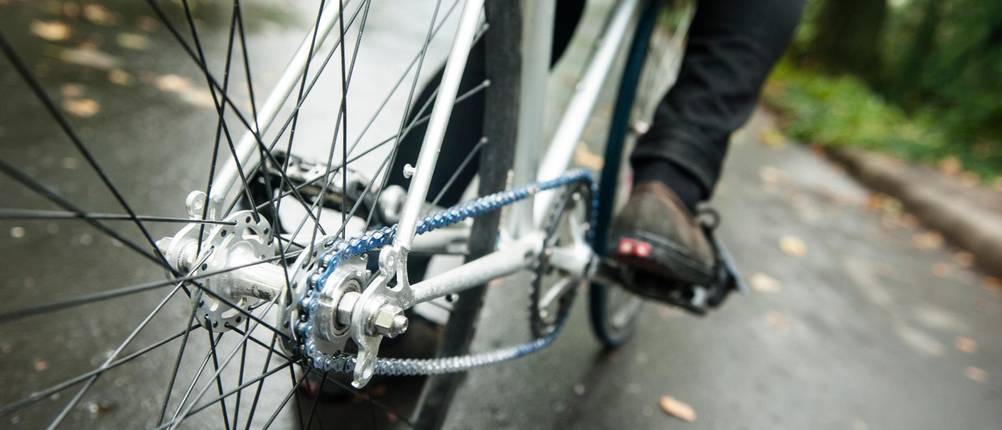Singlespeed Bike Test: Nahaufnahme Kette; Fahrrad wird auf nasser Straße gefahren
