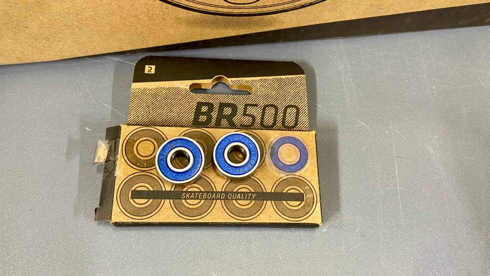 Auf einer Verpackung liegen zwei getestete Skateboard-Kugellager in blau.