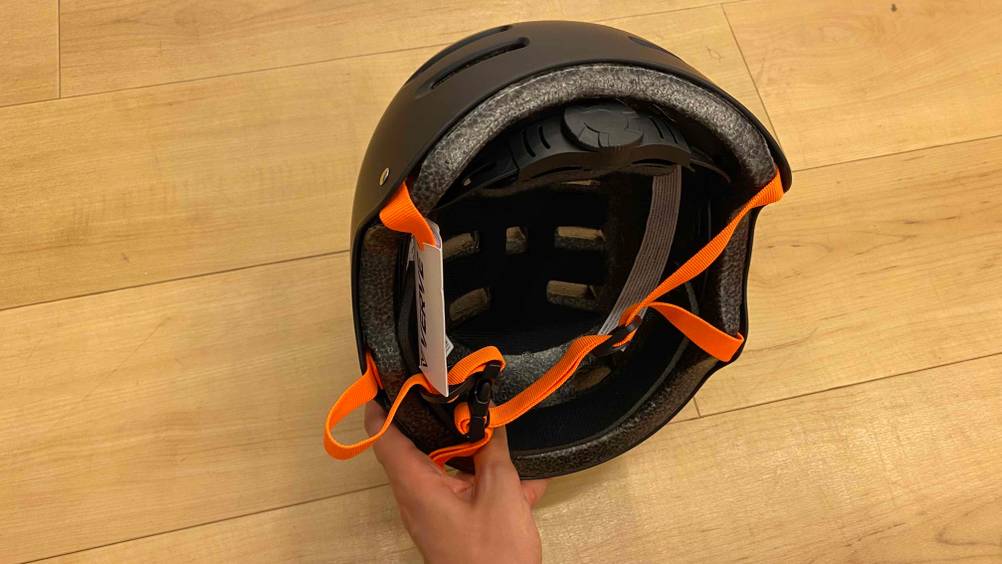 Eine Hand hält einen getesteten Skaterhelm.