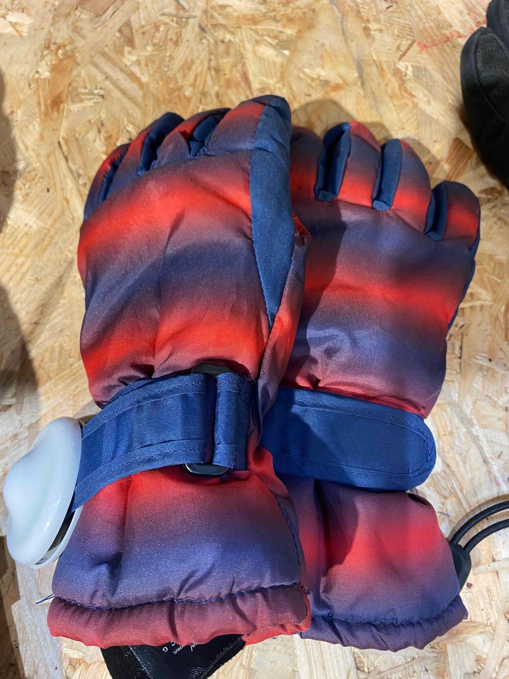 Auf einem Holztisch liegt ein Paar getestete Skihandschuhe für Damen.