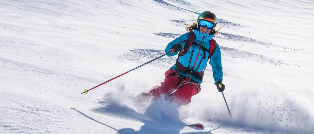Skijacken-Damen-Test: EIne Frau fährt eine Skipiste hinunter.