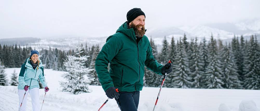 Skipullover-Herren-Test: Ein Mann und eine Frau gehen durch den Schnee.