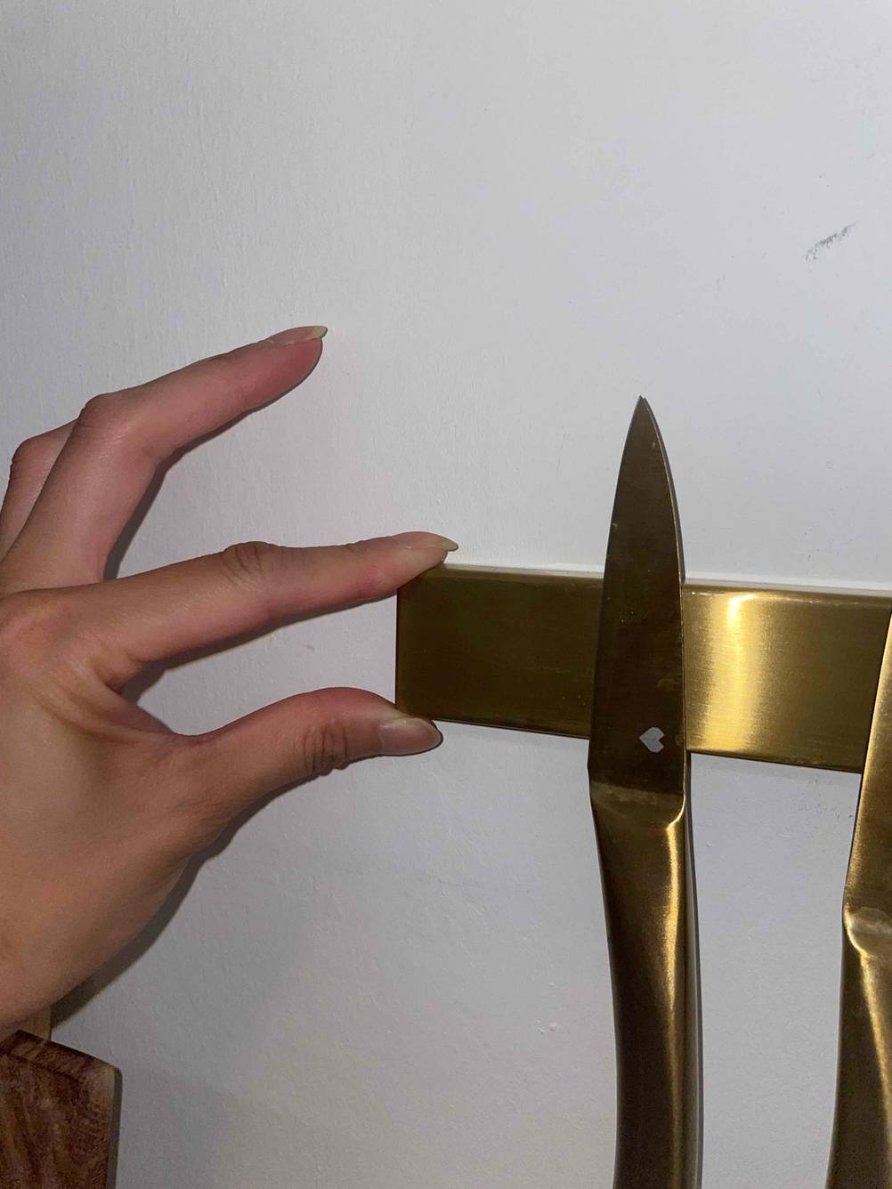 Eine Hand zeigt mit Daumen und Zeigefinger die Höhe einer getesteten Magnetleiste für Messer.