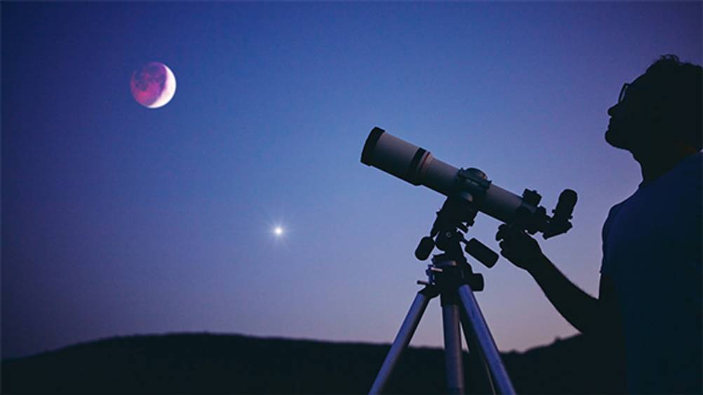 Skywatcher-Teleskop im Test: Ein Mann der mittels Teleskop den Mond betrachtet.