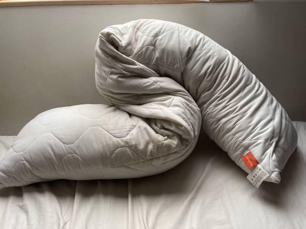 Stäbchenförmiges Sleeping Seitenschläferkissen im Test liegt gefaltet auf einer Matratze.