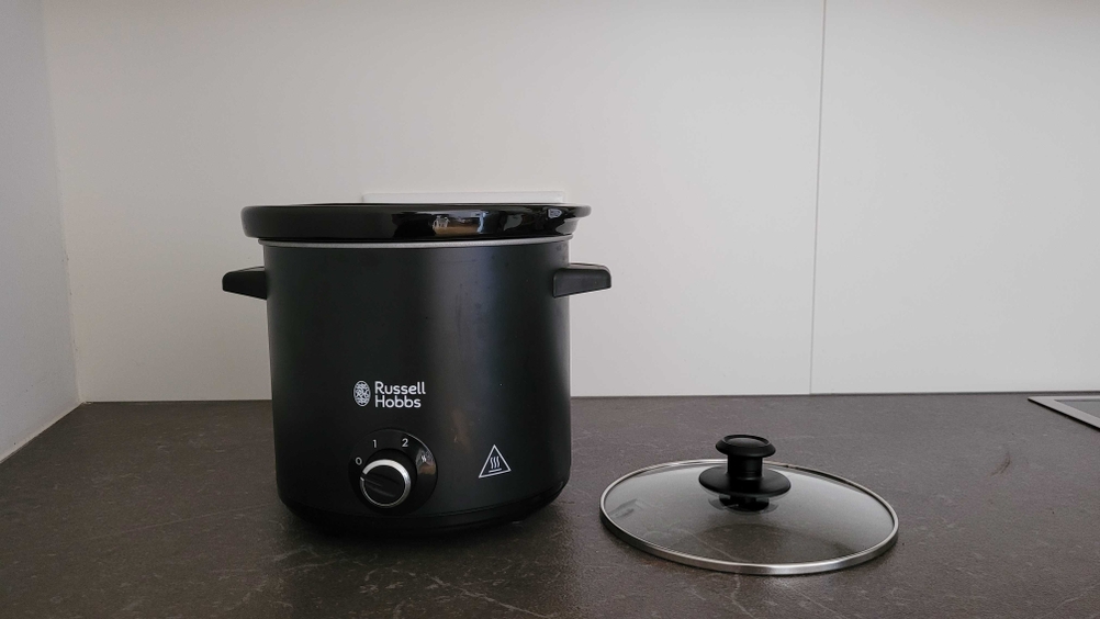 Ein getesteter Slow-Cooker steht neben dem Deckel auf einem Küchentisch. 