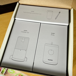 Der Hurom H310A Slow Juicer ist ordentlich in seiner Originalverpackung verstaut. Die einzelnen Komponenten sind in separaten Kartons organisiert.