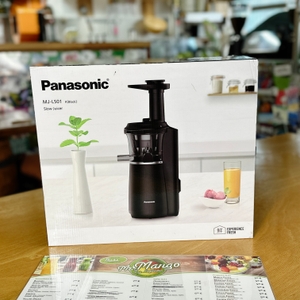  Die Verpackung des Panasonic MJ-L501KXE Slow Juicers steht auf einem Holztisch. Im Hintergrund ist eine Café-Umgebung mit verschiedenen Deko-Elementen.