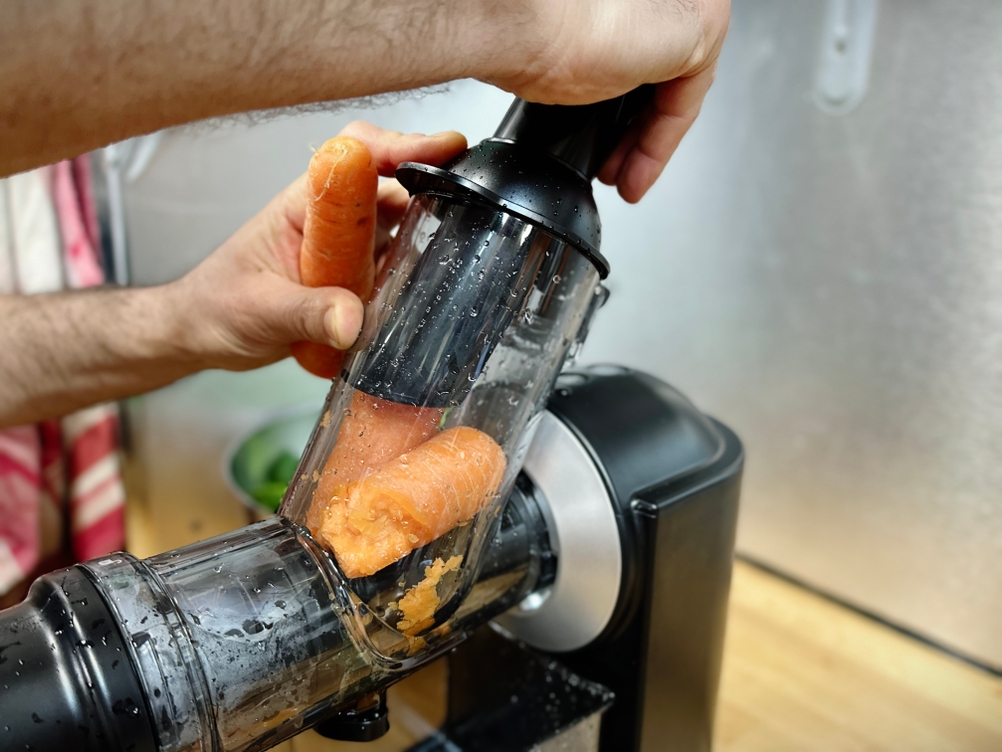 Der Einfüllstutzen des Philips Entsafters ist sichtbar von einer Karotte verstopft. Ein Nutzer versucht sie mit dem Stößel zu lösen.