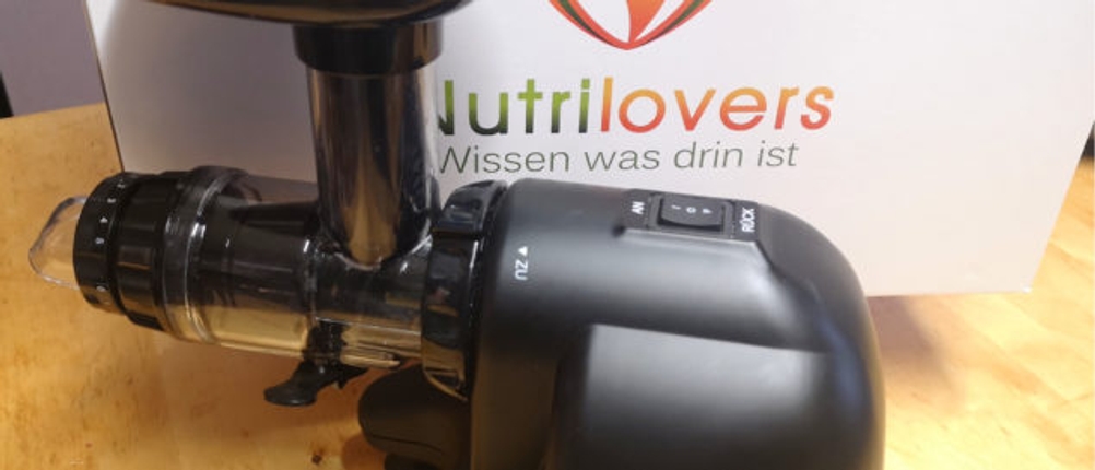 Ein Slow-Juicer im Test steht vor der Verpackung von Nutrilovers.