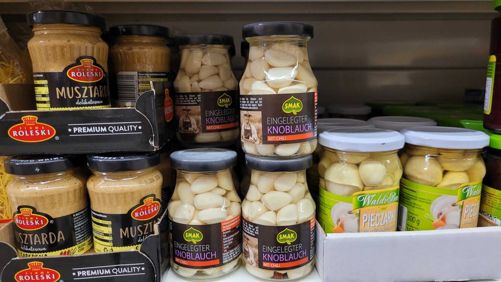 Der eingelegte Knoblauch im Test steht in einem Regal zwischen Senfgläsern im Supermarkt.