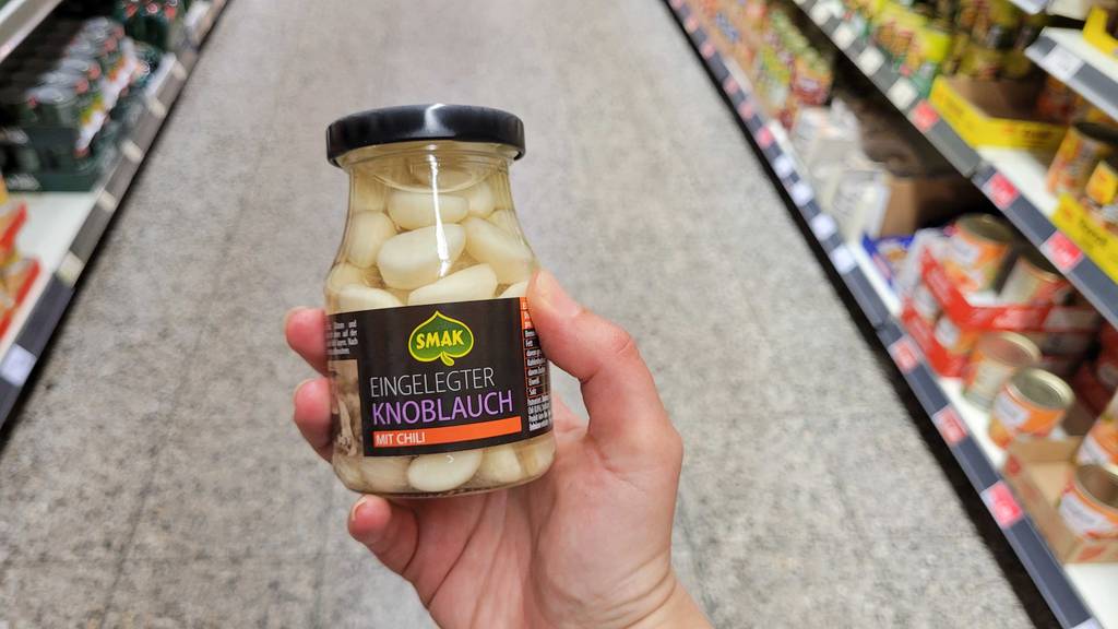 Getestet: Der eingelegte Knoblauch wird im Supermarkt von einer Hand gehalten.