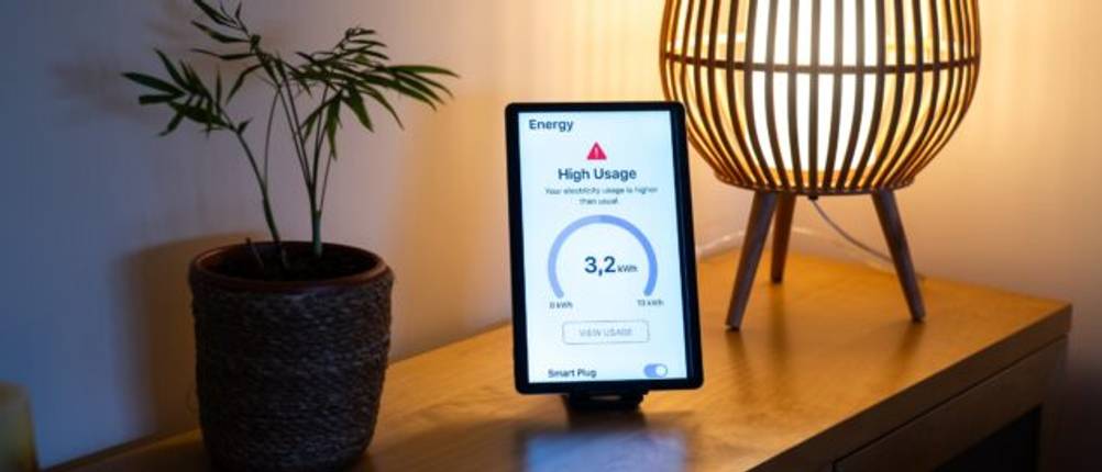 Auf einem Sideboard steht ein Tablet, welches eine Warnung wegen eines hohen Stromverbrauchs anzeigt.